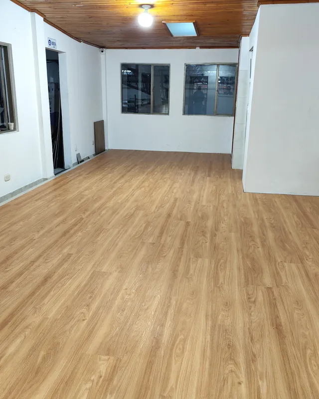 Espacio vacío con ventanas y piso tipo madera en tono dorado